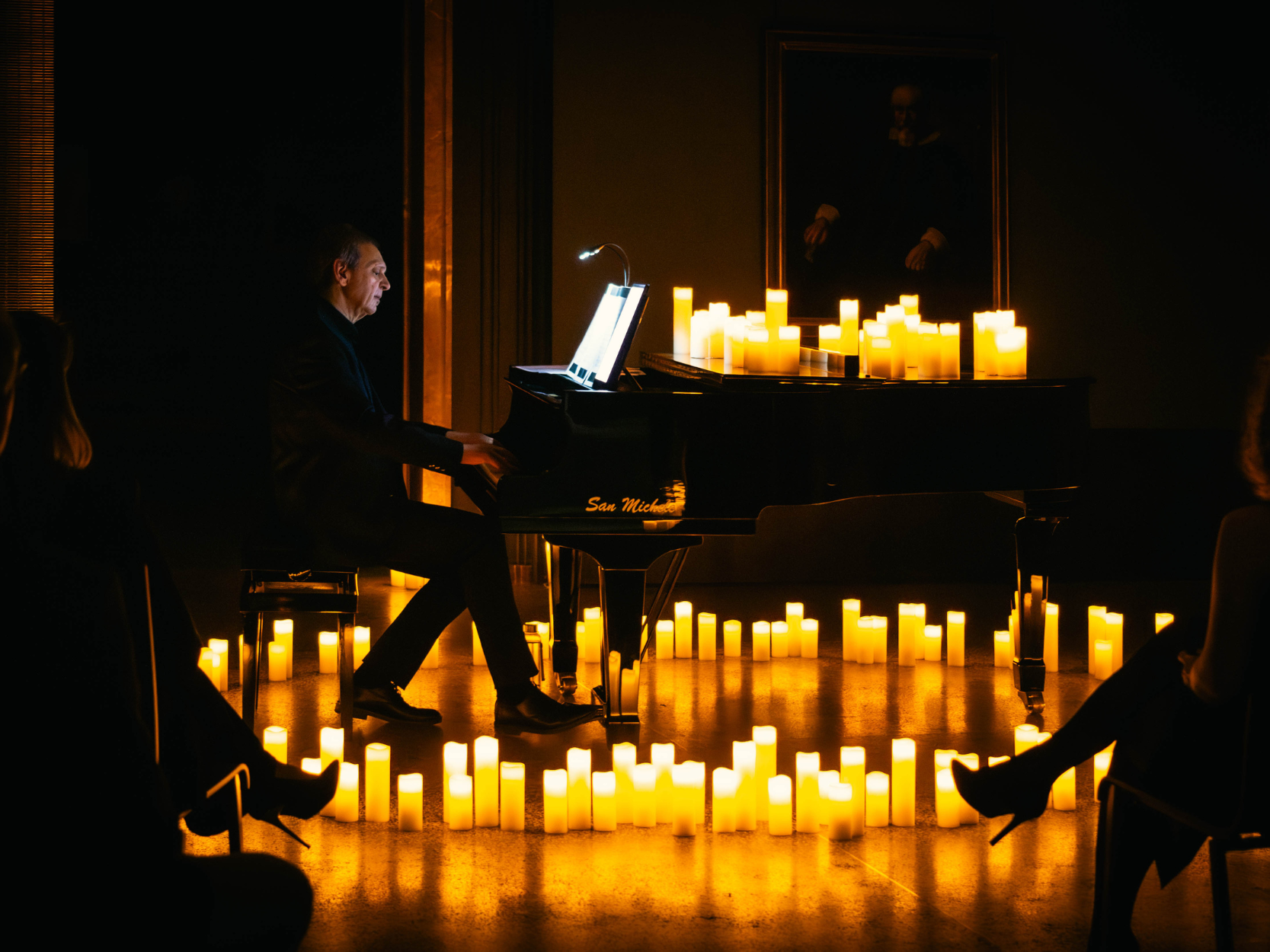 Uomo che suona il pianoforte circondato da candele di notte